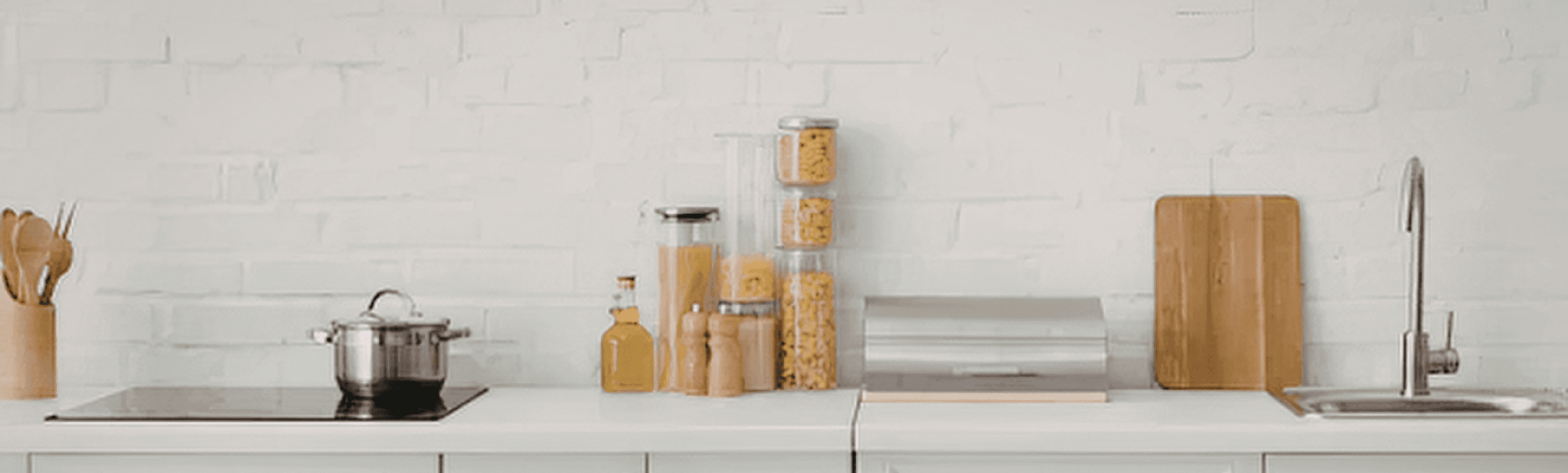 A bright kitchen counter lined with glass pantry jars and cutting boards