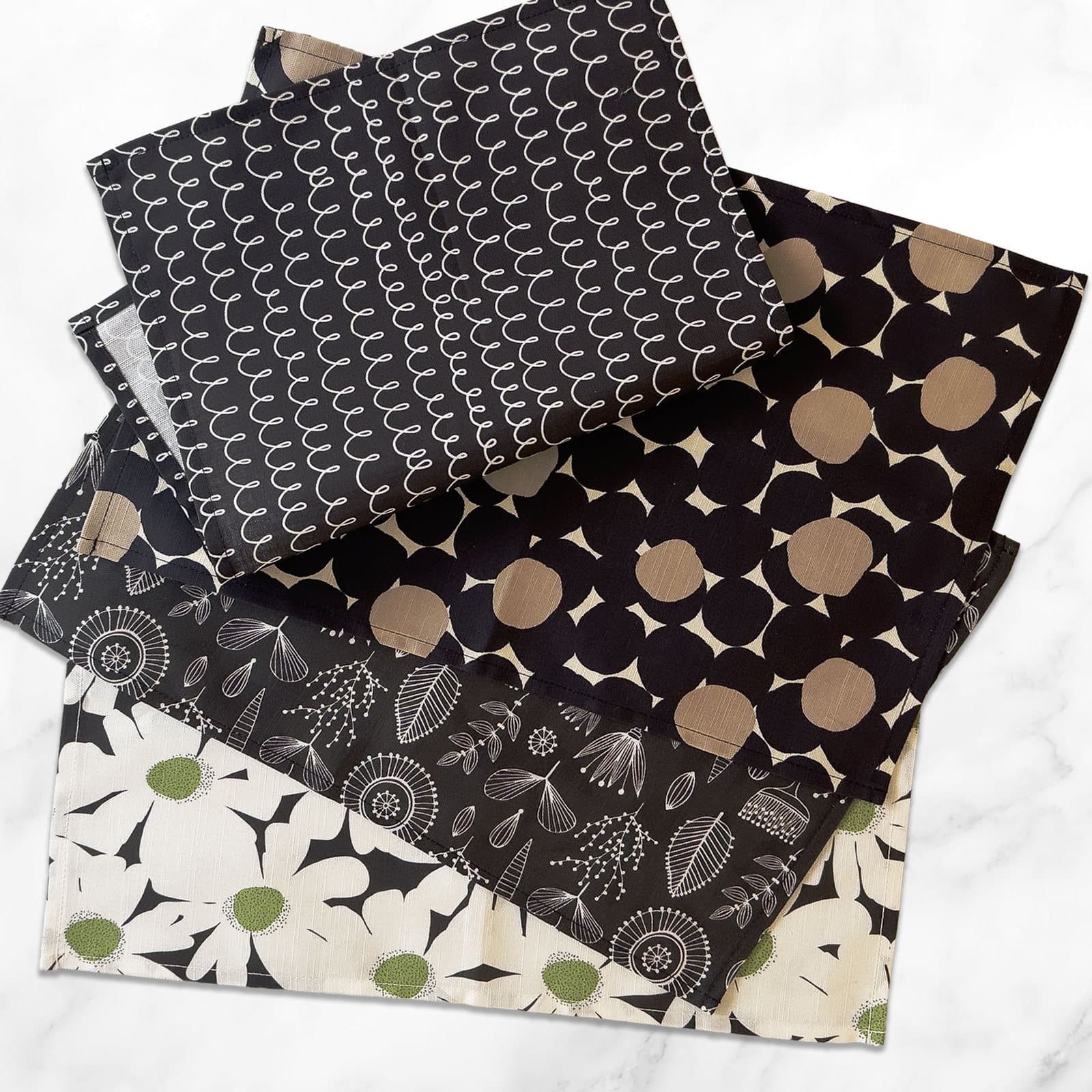 Four linen cotton placemats stacked, showing the daisy, dot, line, and leaf Scandinavian prints